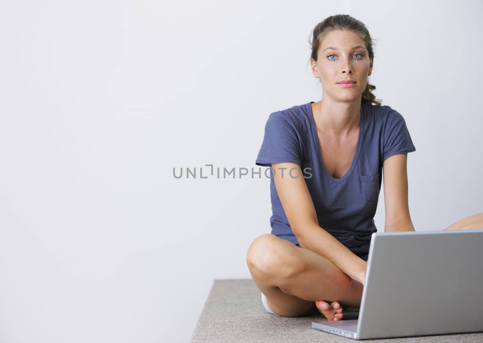 Portrait of beautiful young girl sitting on floor and using a laptop at home 