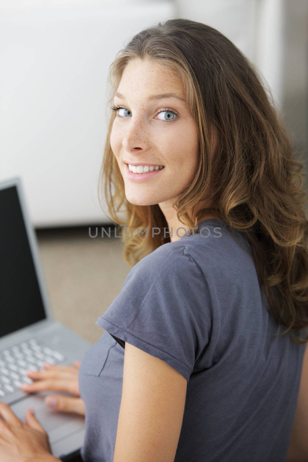 Closeup portrait of a happy young woman working on laptop