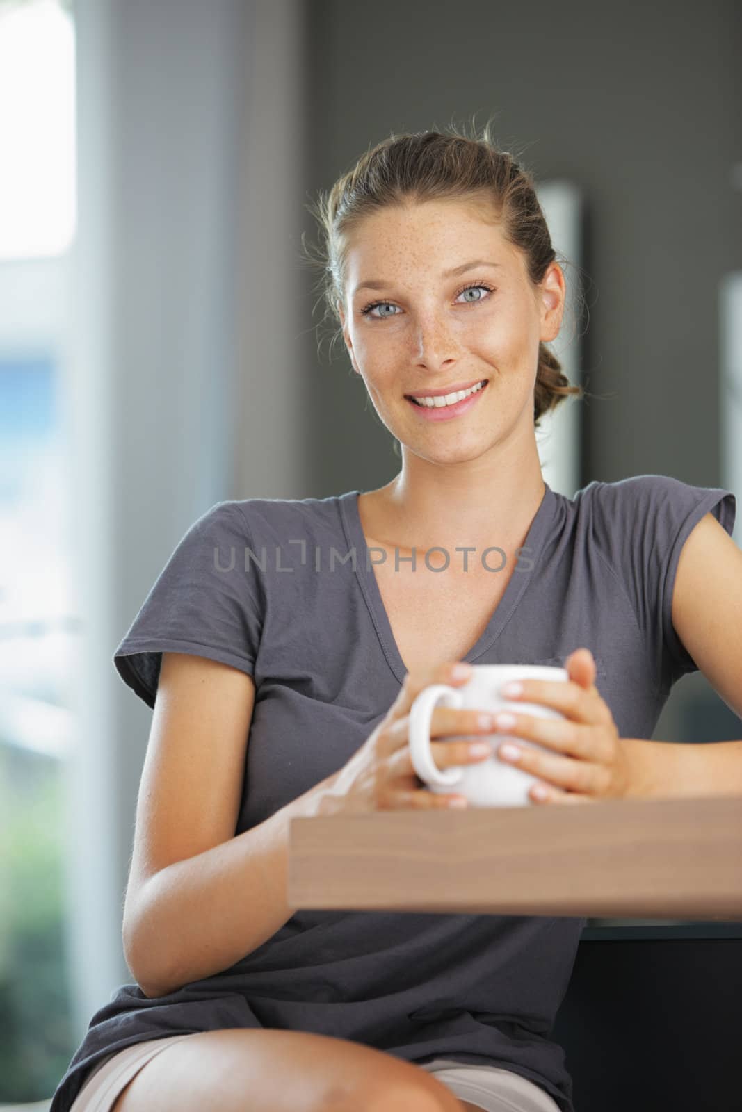 Young smiling woman sitting with a cup of coffee
