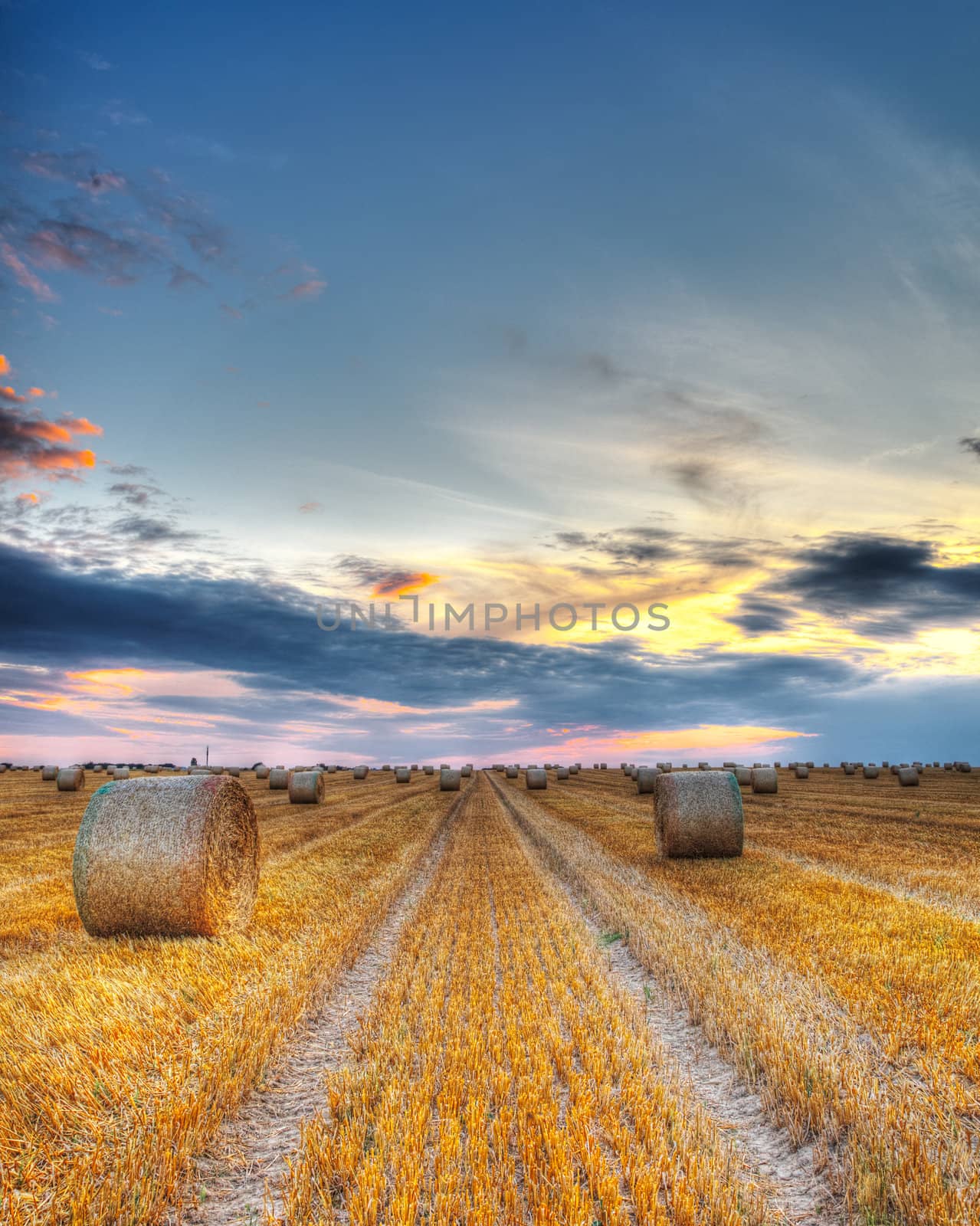 Beautiful sunset over a field with bales of hay.