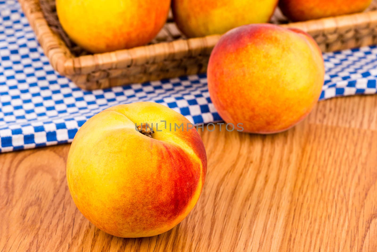 Fresh peaches in the basket on a wooden table.