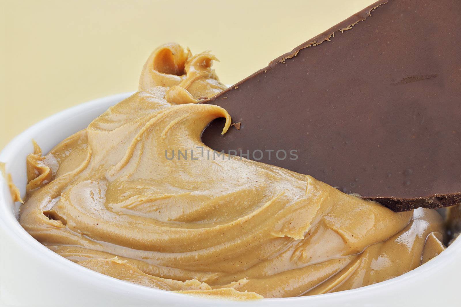 Peanut butter with a piece of a chocolate candy bar dipped into it.

