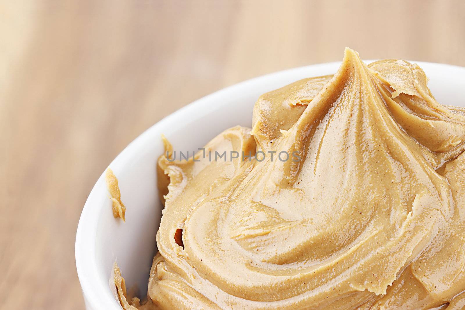 Creamy peanut butter in a dish with shallow depth of field.
