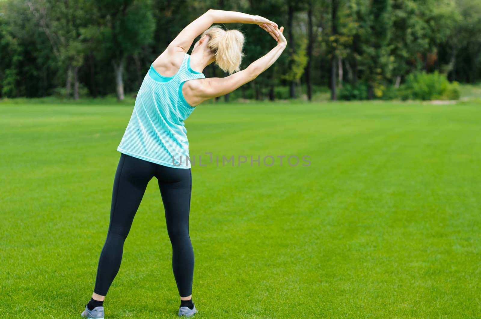 Woman doing overhead stretches as she is standing in the grass