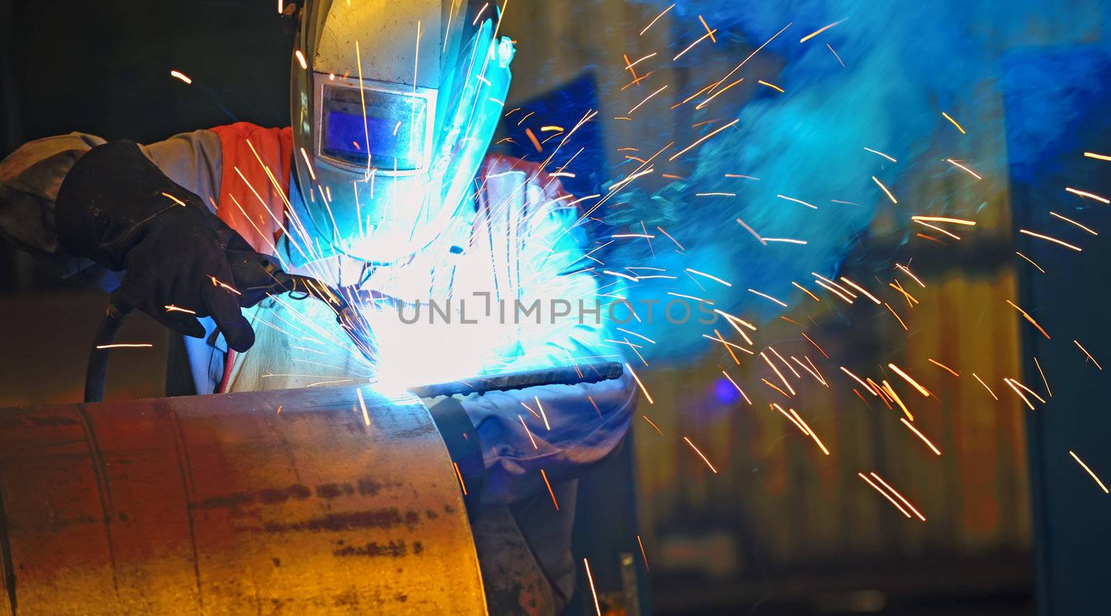 worker with protective mask welding metal and sparks