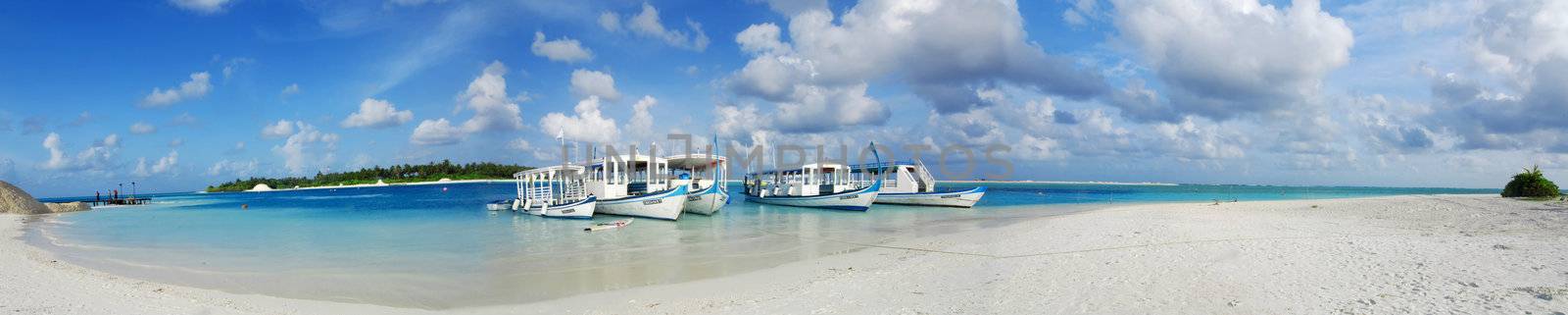 Beautiful white Maldivian beach and five dhoni ships docked nearby