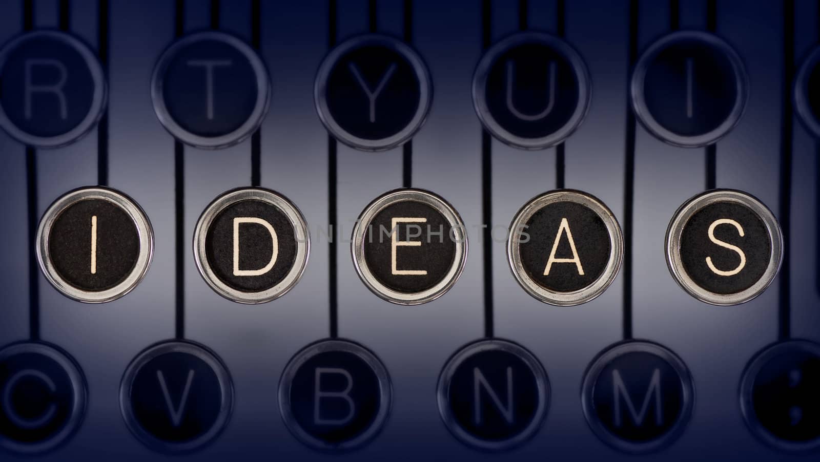 Close up of old typewriter keyboard with scratched chrome keys that spell out "IDEAS". Lighting and focus are centered on "IDEAS". 