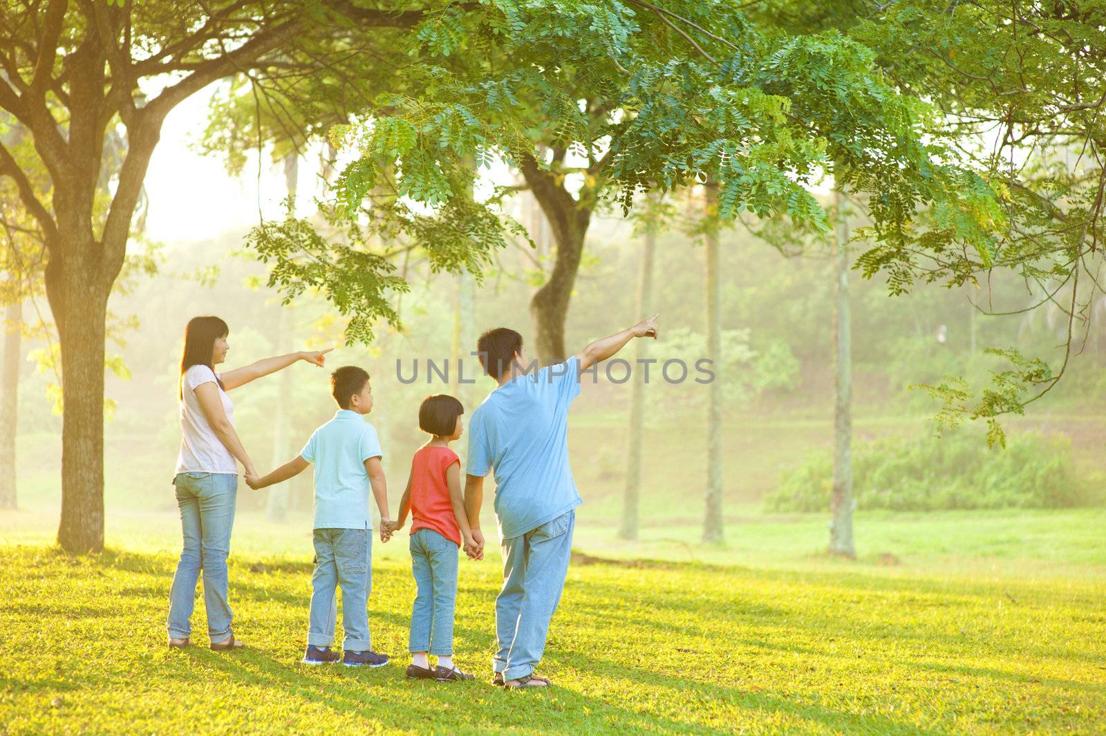 Candid Asian family pointing at outdoor park