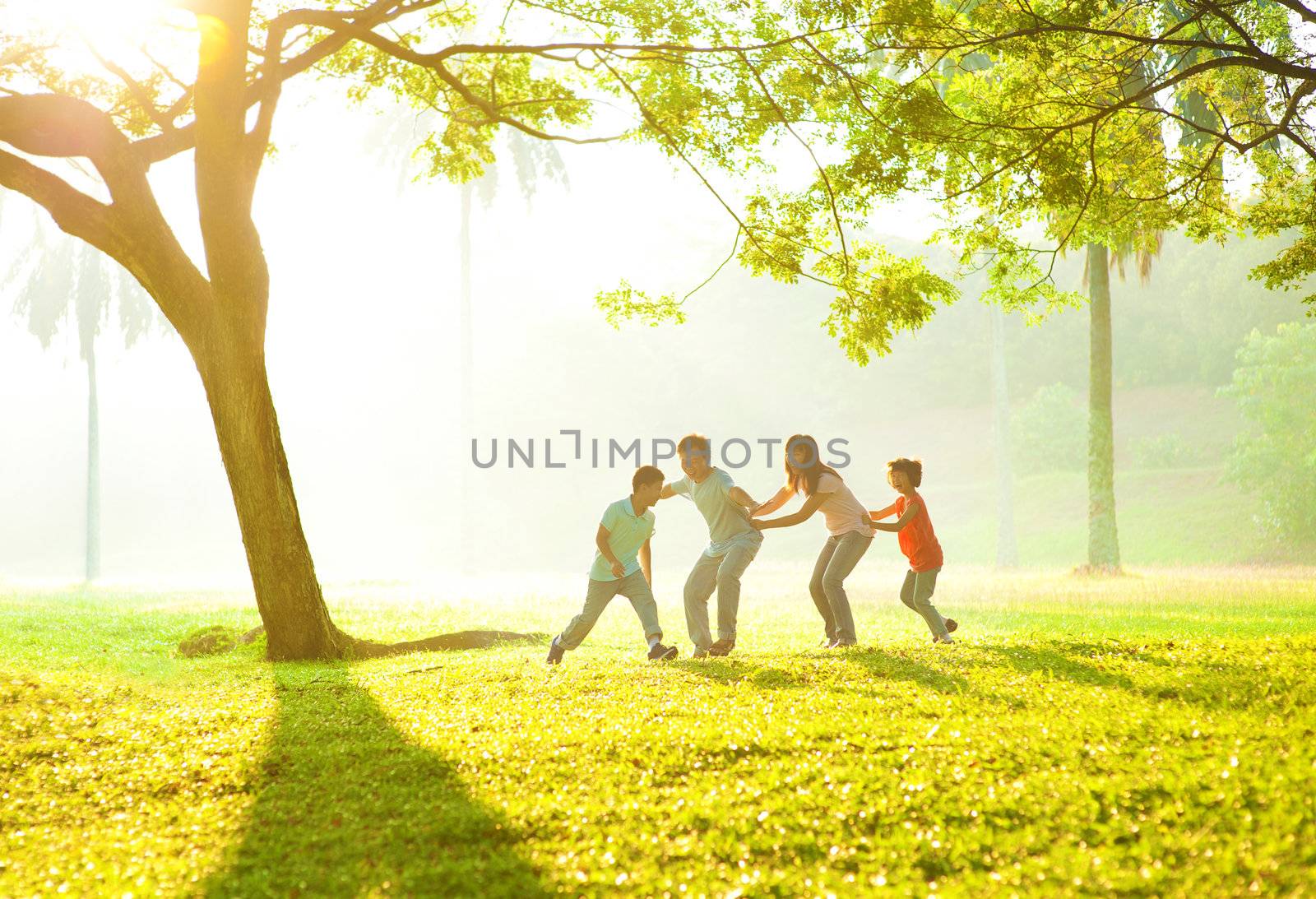 Happy Asian family playing together at outdoor park