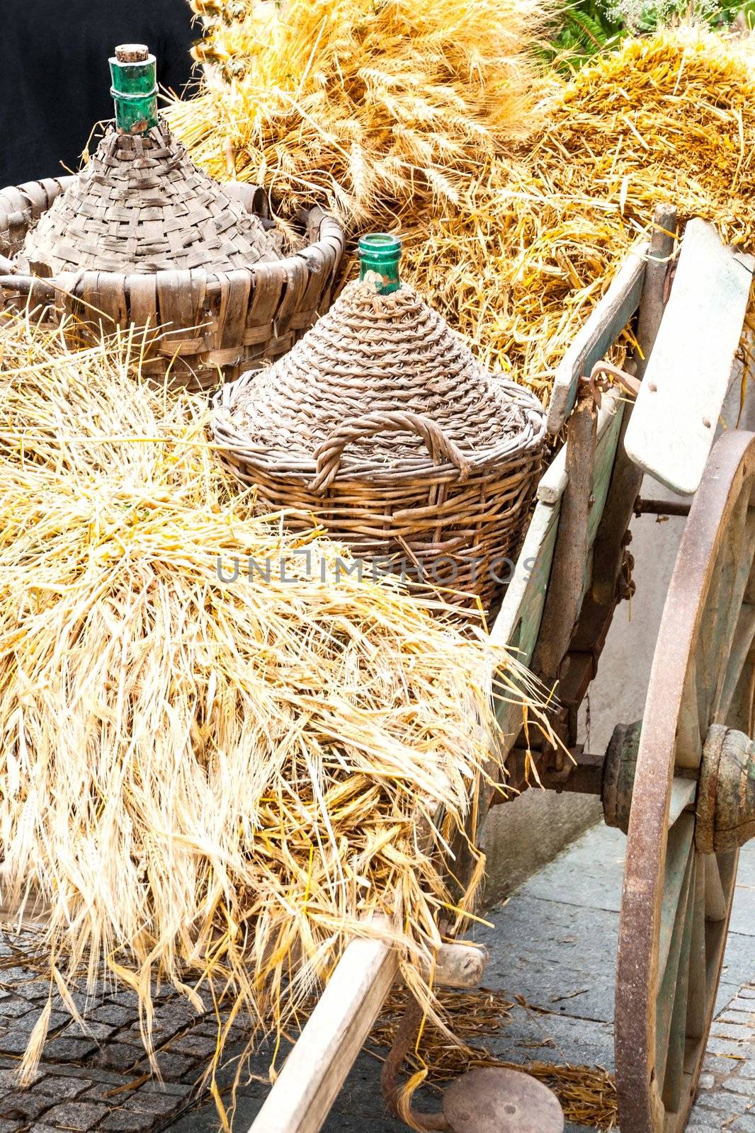 Autumn wooden cart harvest and demijohn wicker with bales of hay