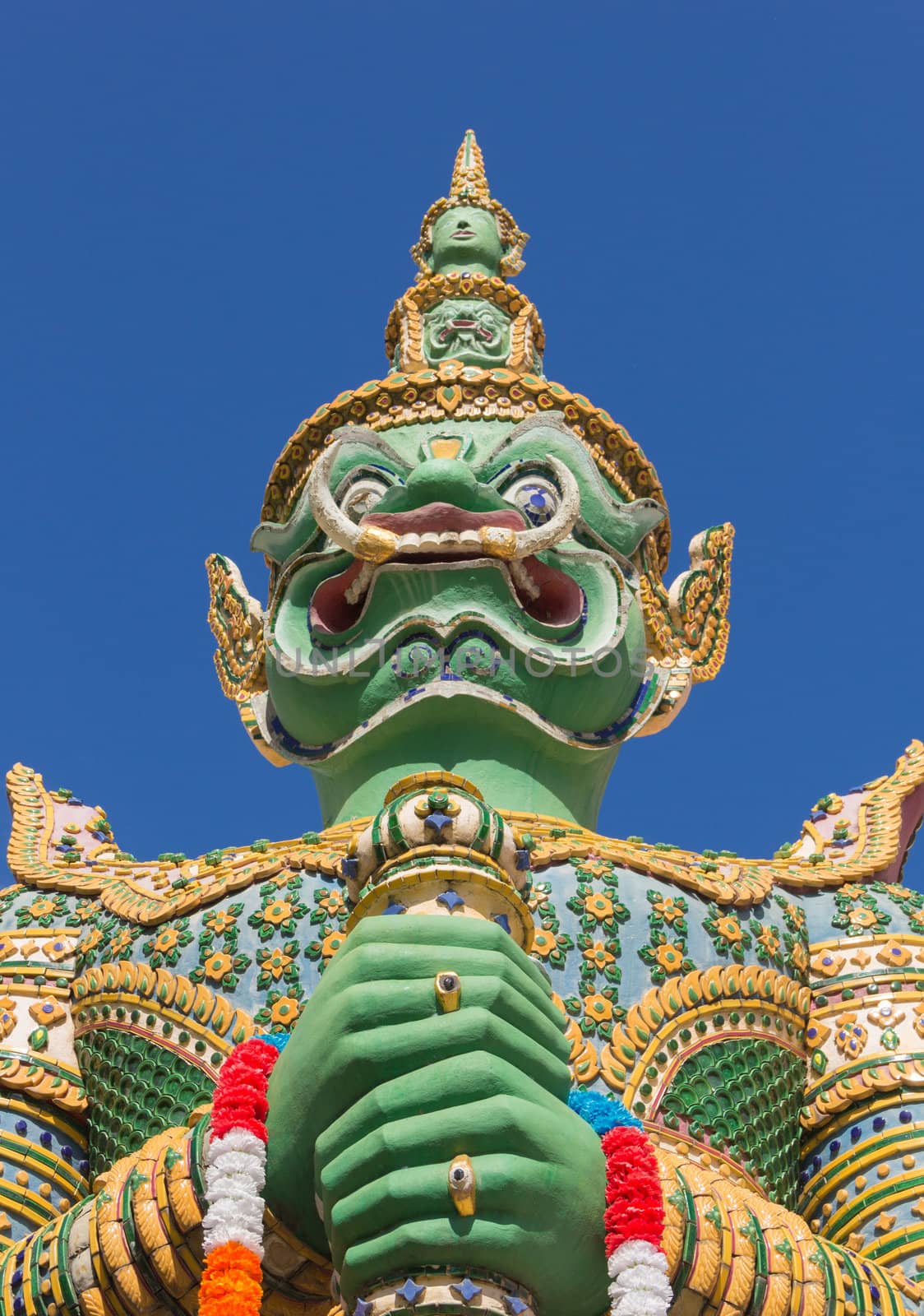 Demon Guardian statue at the Temple of Dawn was beautifully decorated with tiny pieces of colored ceramics and Chinese porcelain placed delicately into intricate patterns. It is one of Bangkok's world-famous landmarks.