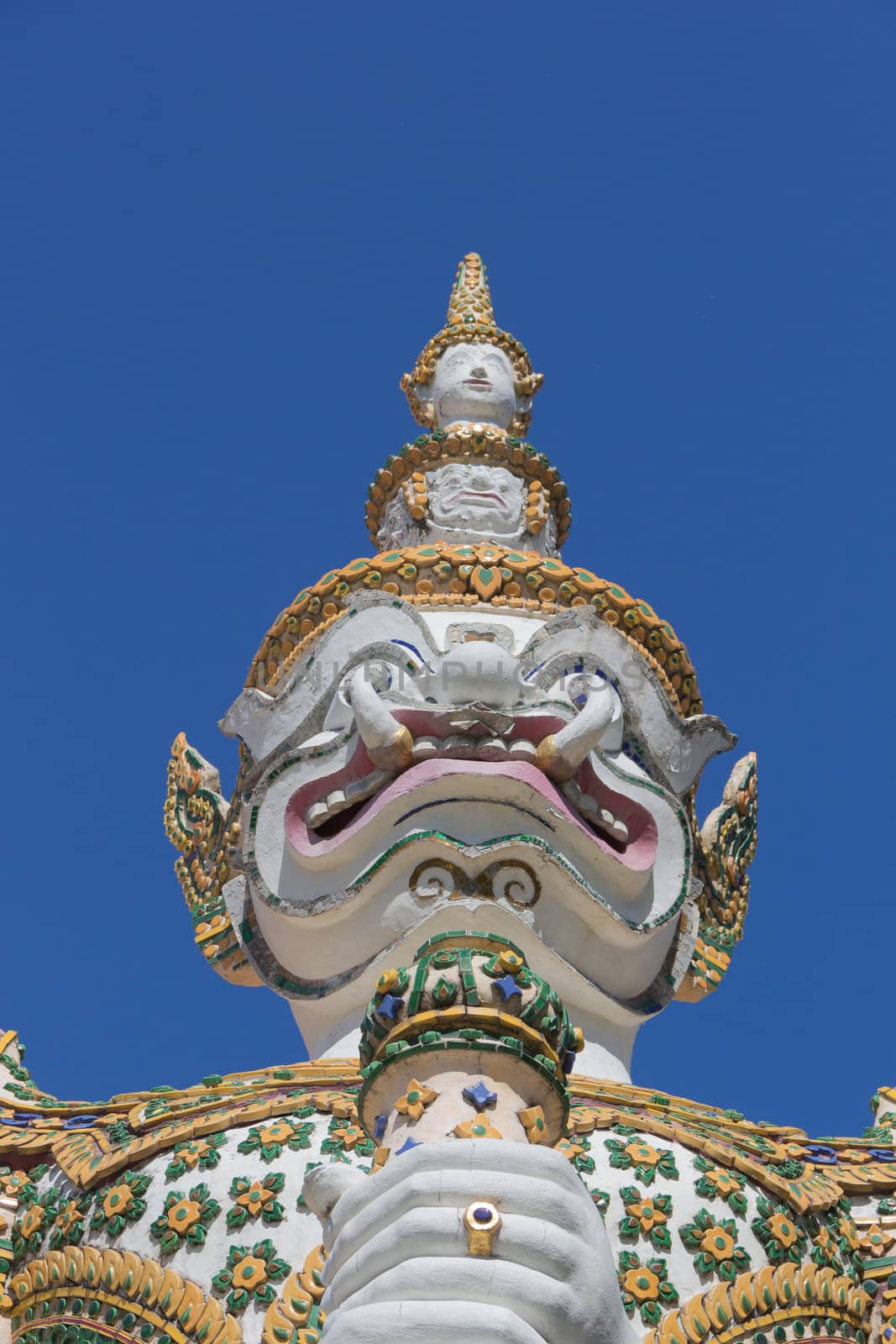 White guardian statue at the Temple of Dawn was beautifully decorated with tiny pieces of colored ceramics and Chinese porcelain placed delicately into intricate patterns. It is one of Bangkok's world-famous landmarks.