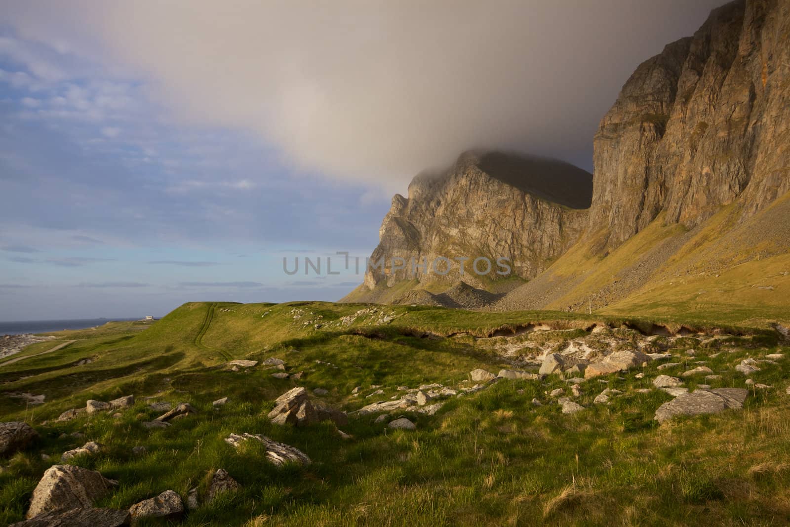 High cliffs in clouds along the coast of island of Vaeroy on Lofoten islands in Norway