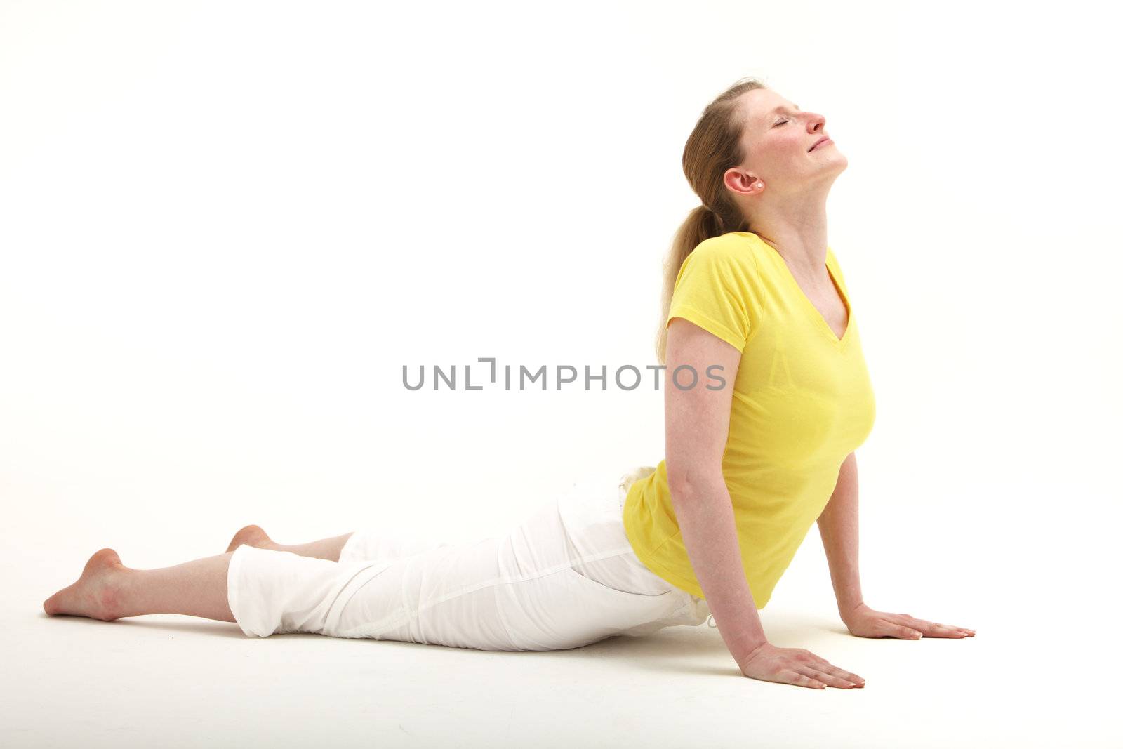 Attractive fit slender woman lying on the floor doing push ups and holding the raised position with her eyes closed and a look of tranquillity on her face 