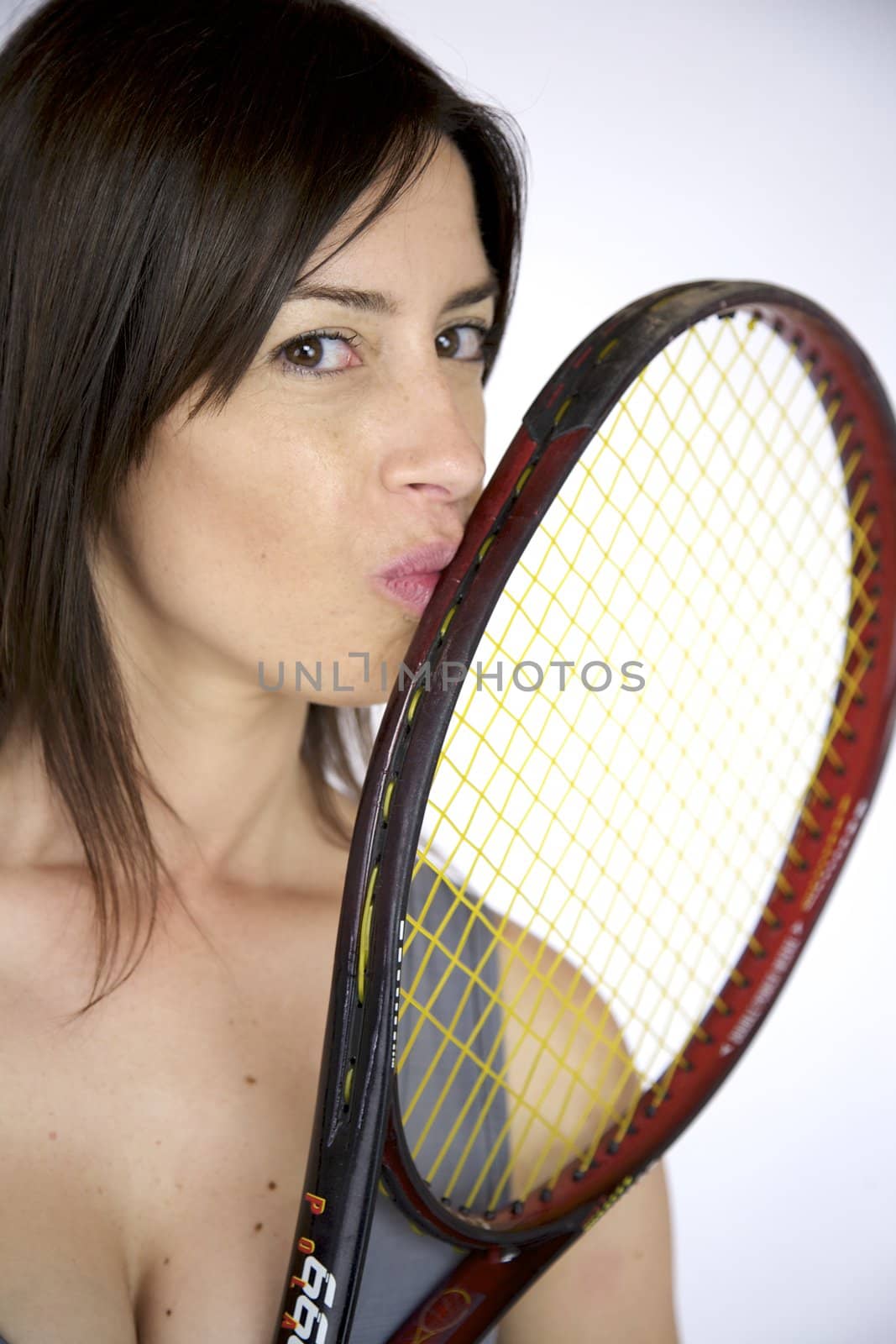 Happy young woman kissing her tennis racquet after victory studio shot