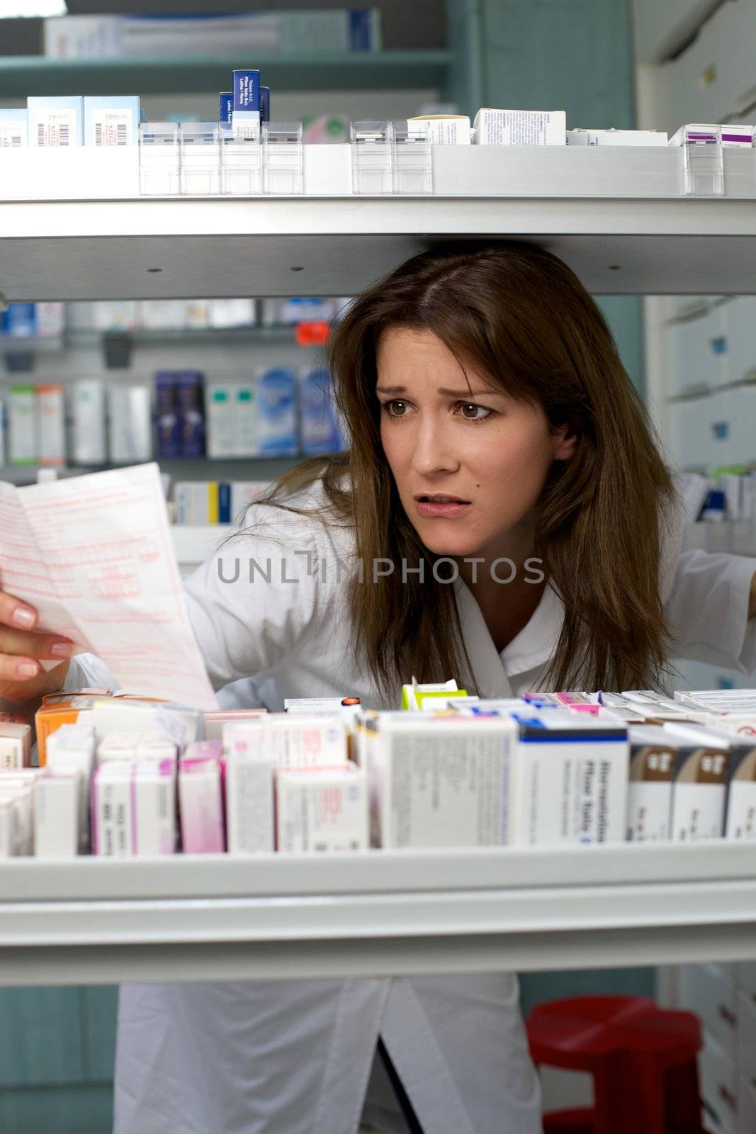 Woman work in pharmacy looking prescription by fmarsicano