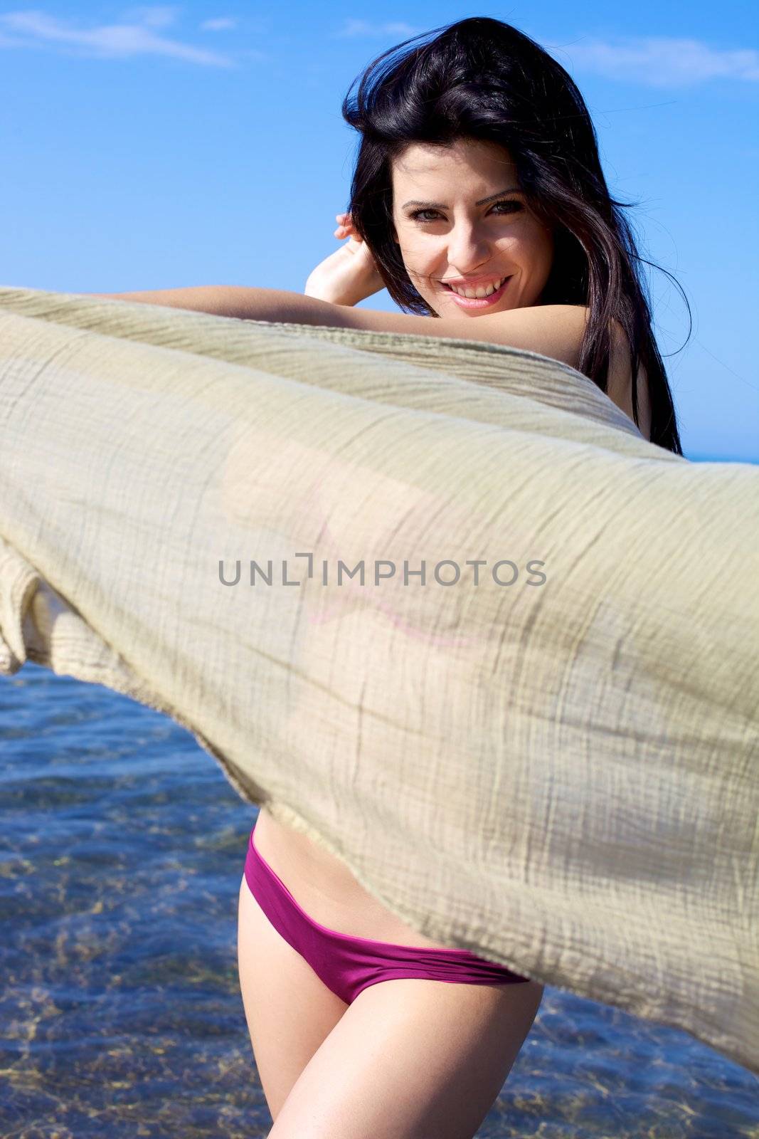 Beautiful woman in the sea playing smiling with veil