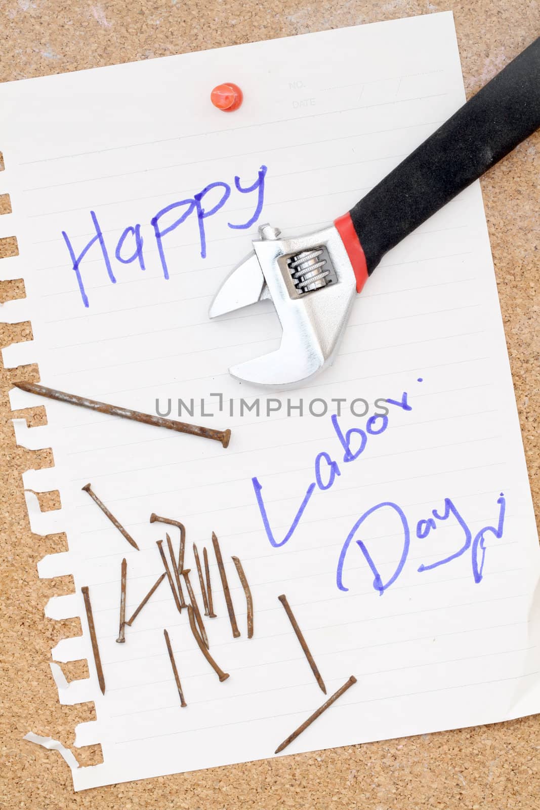 wrench and rusty nails with paper attach to cork board for labor day