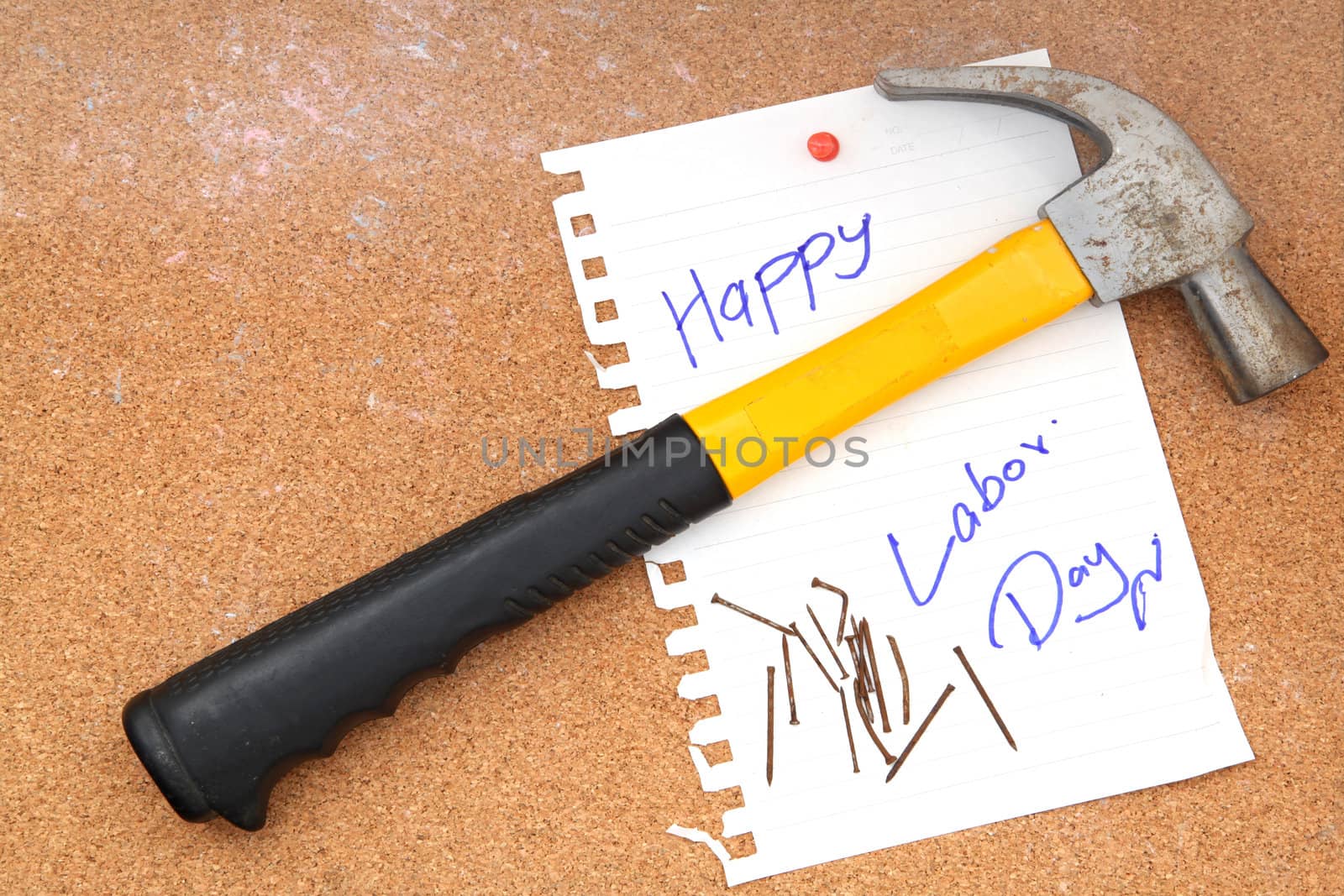 hammer and rusty nails with paper attach to cork board for labor day