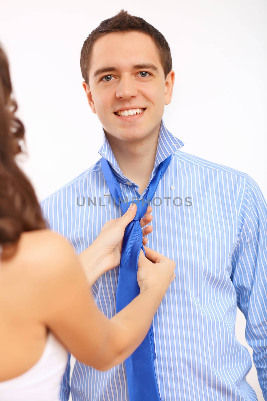 Young businessman dressing at home in the morning. Woman helping to fasten his tie