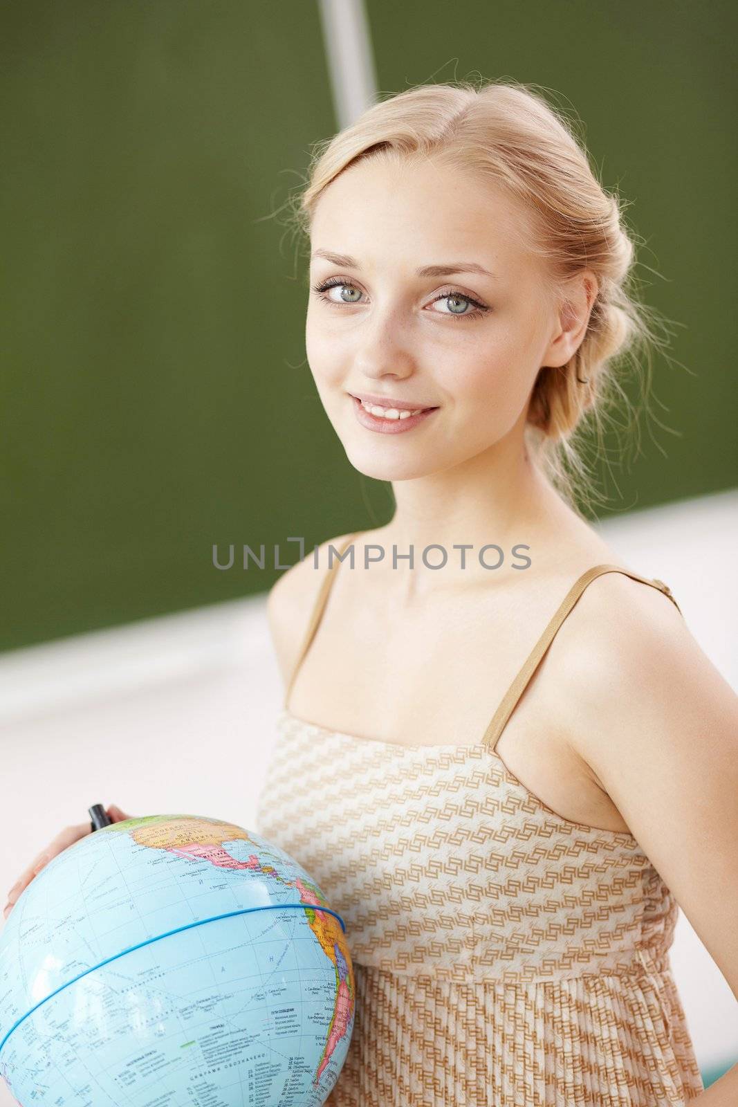 Young female teacher holding a globe at school