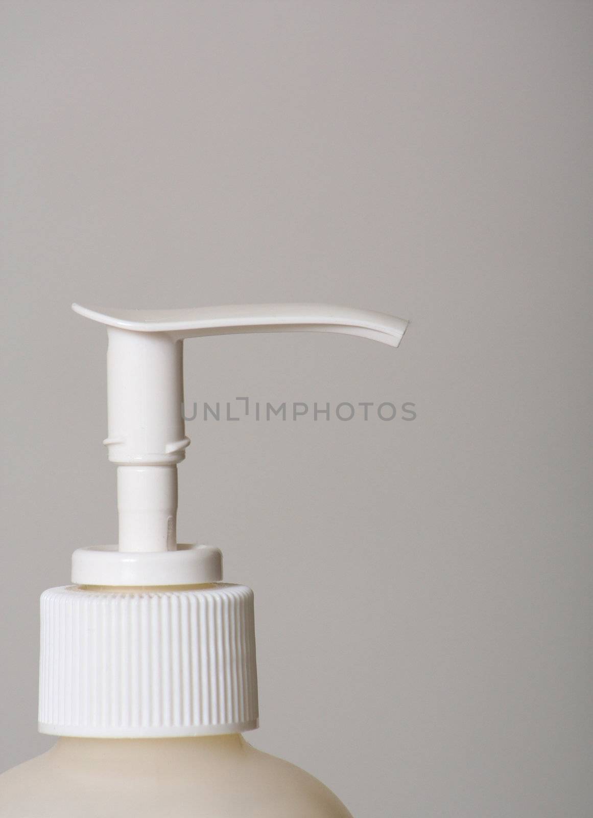 The top of a bottle of lotion isolated against a gray background