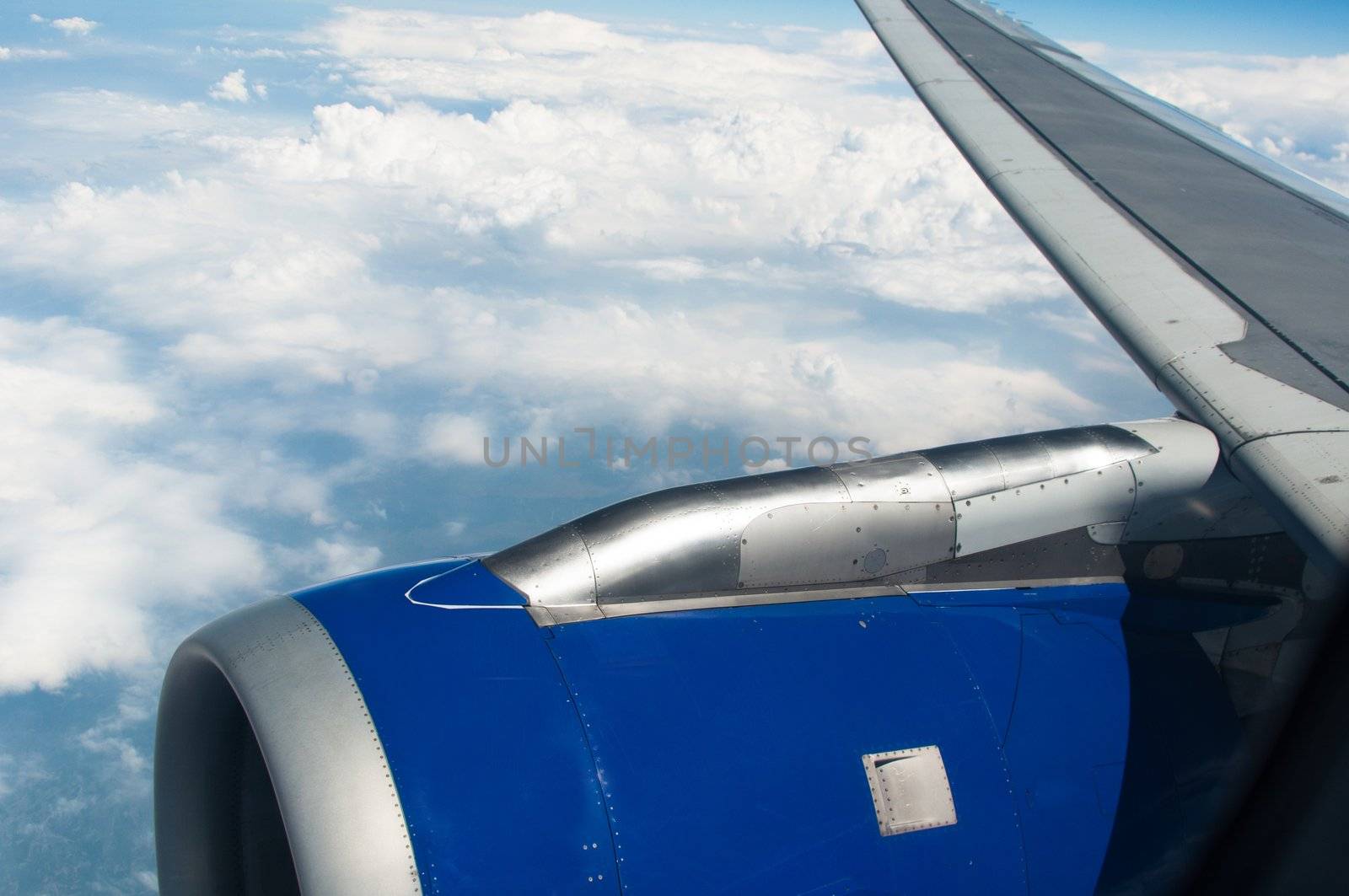 airplane wing, turbine, sky and clouds as seen through the cabin window