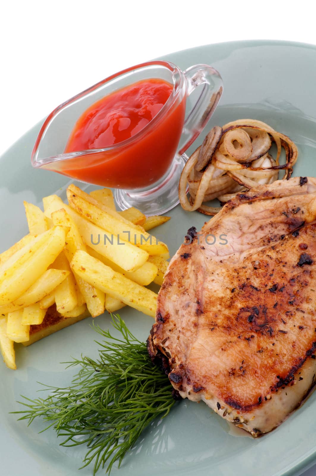 Pork Steak, French Fries and Grilled Onions with Ketchup and Dill close up on green plate