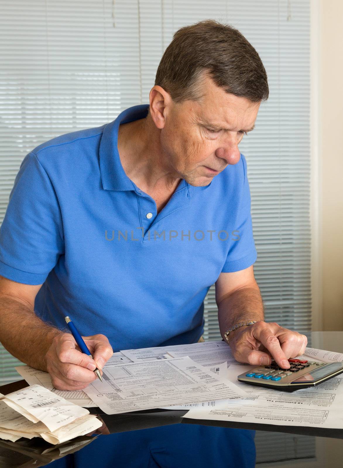 Senior caucasian man preparing tax form 1040 for tax year 2012  with receipts and calculator