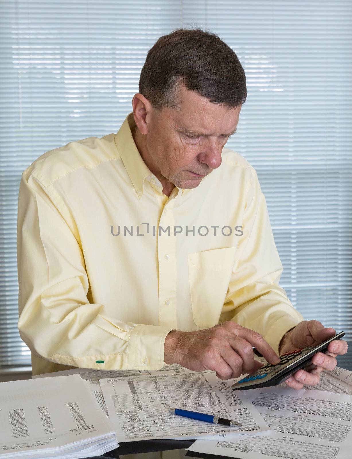 Senior caucasian man preparing tax form 1040 for tax year 2012  with receipts and calculator