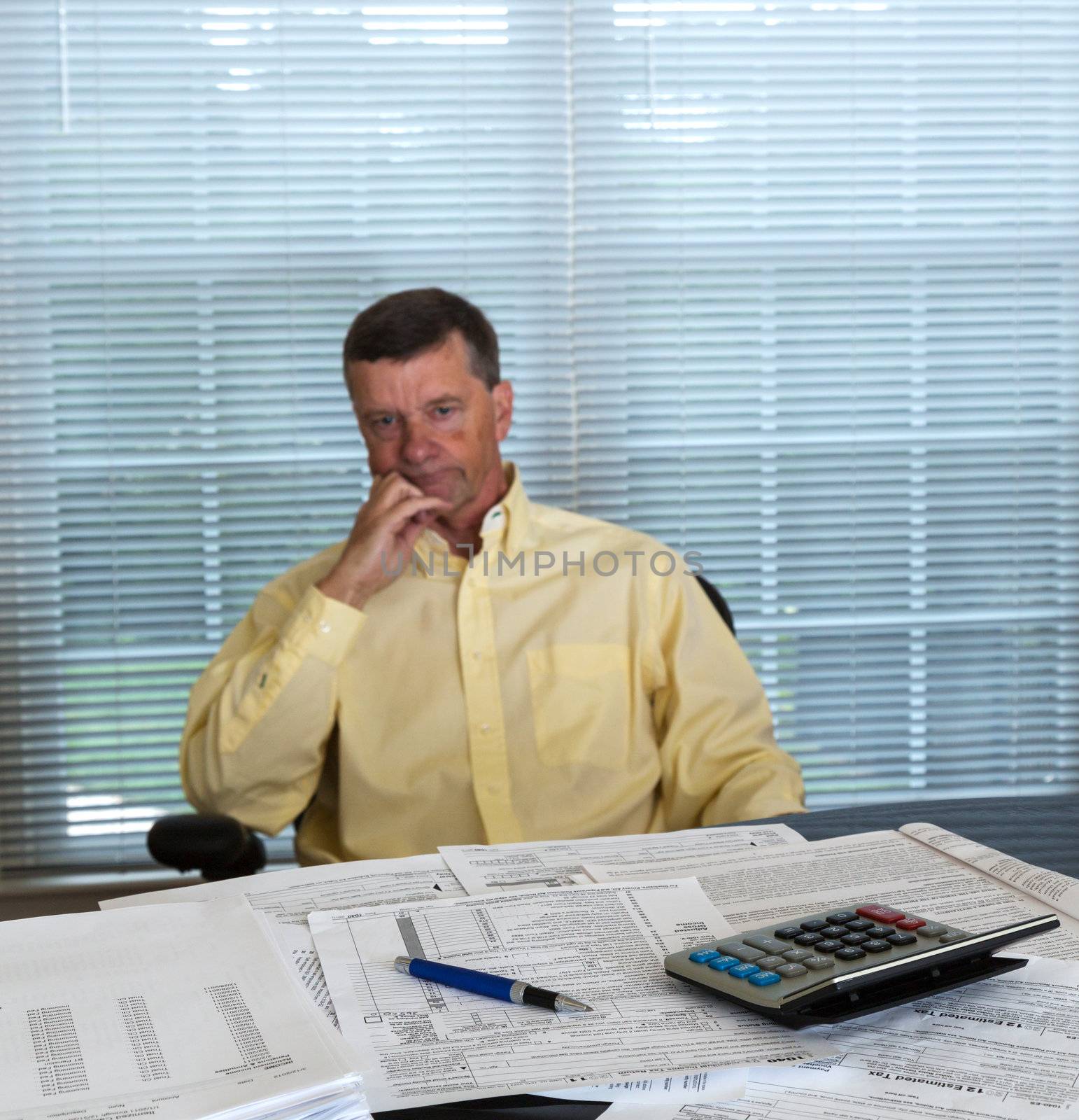 Senior caucasian man weary from preparing tax form 1040 for tax year 2012  with calculator