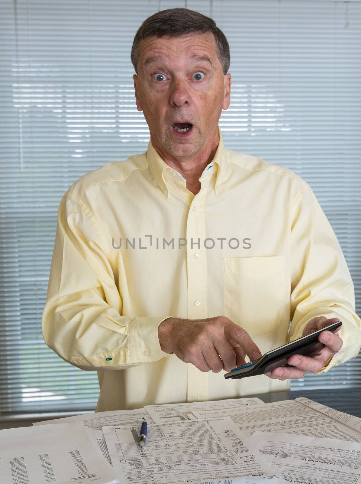 Senior caucasian man preparing tax form 1040 for tax year 2012  showing shock at amount of tax owed