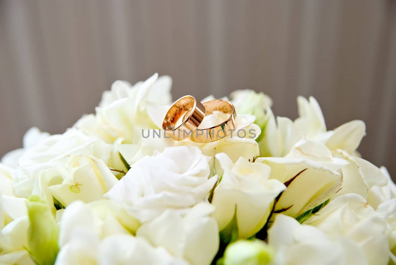 Wedding rings on a bridal bouquet of white roses