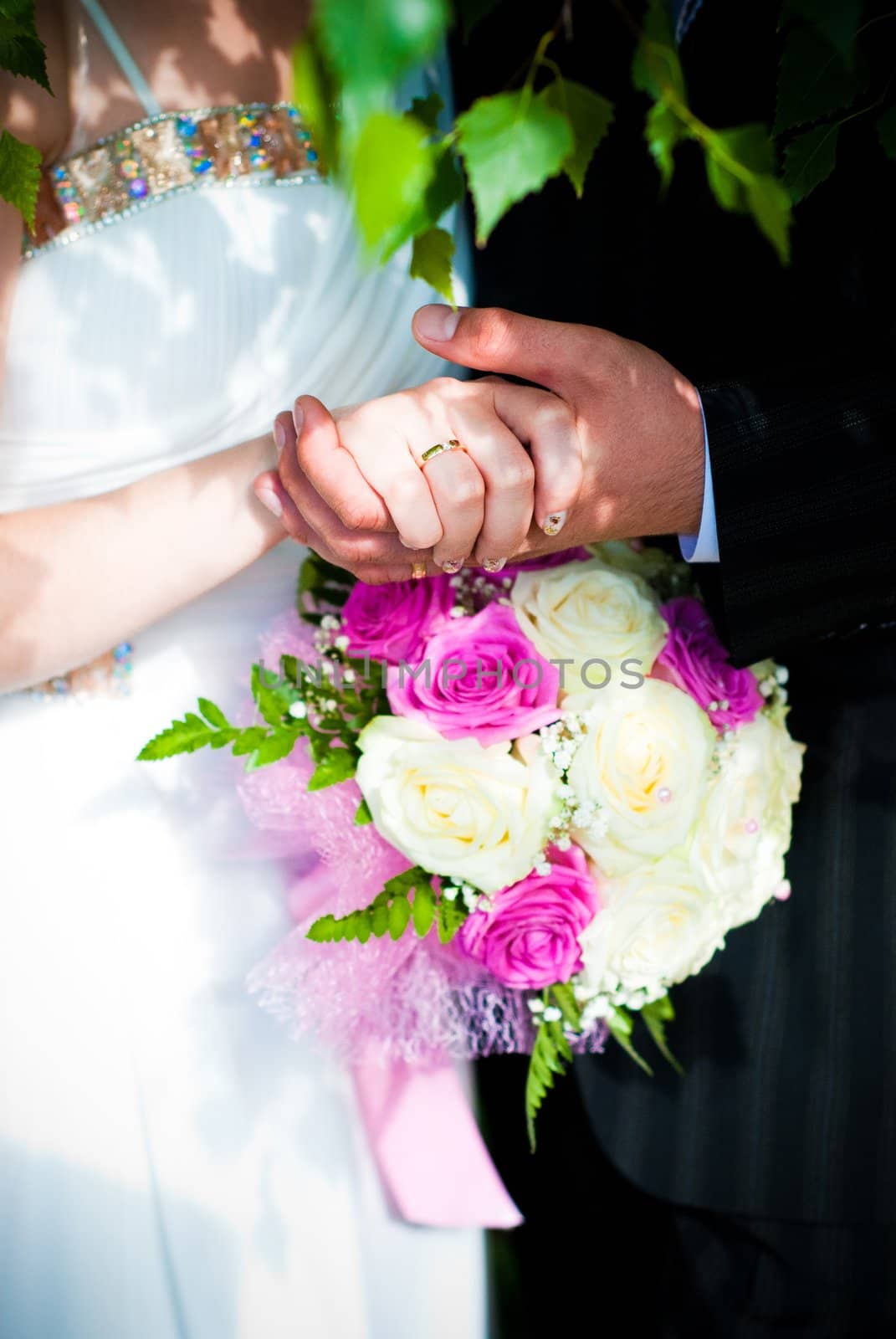 Bridal bouquet of white roses and hands of newlywed