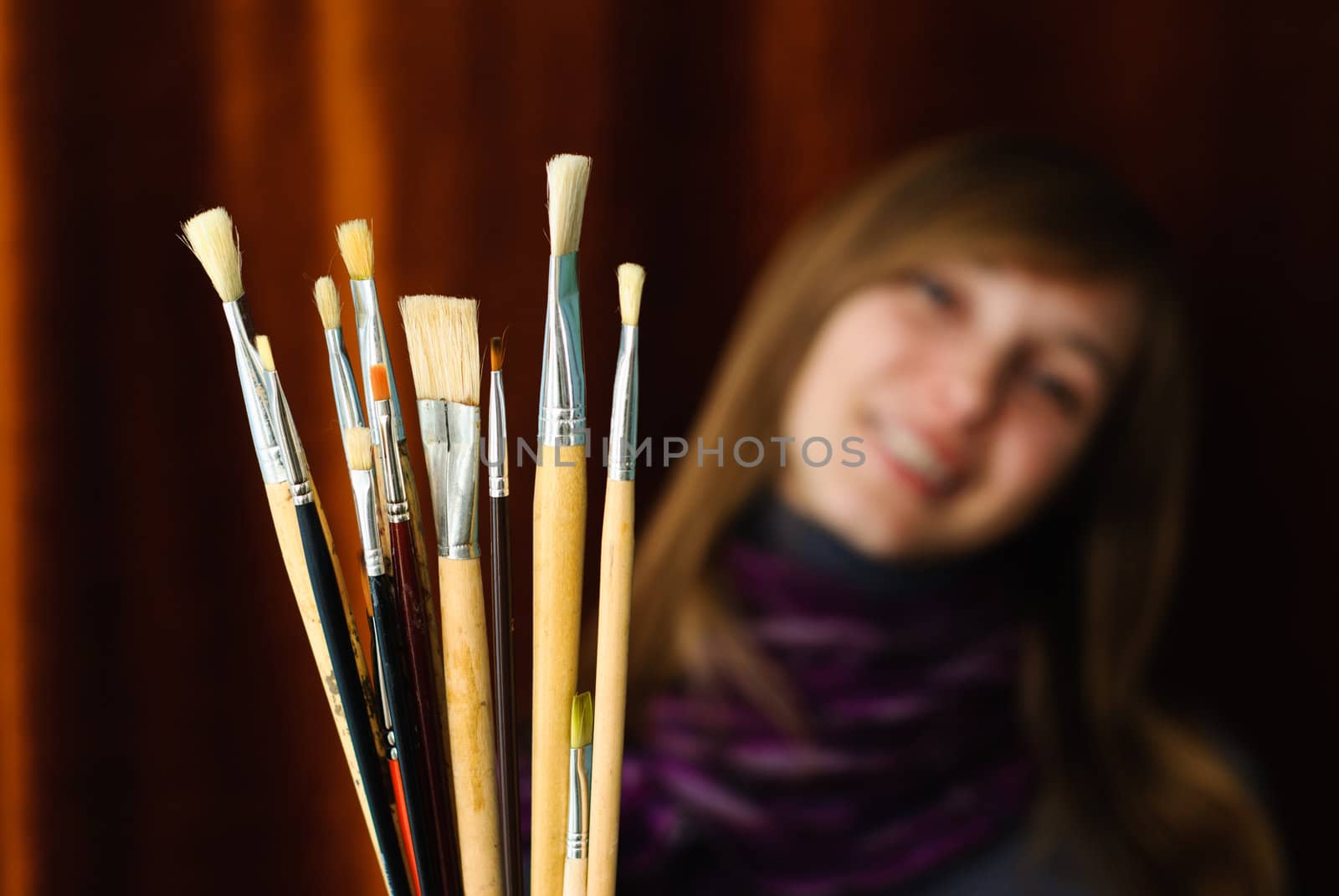 Portrait of young female artist with brushes