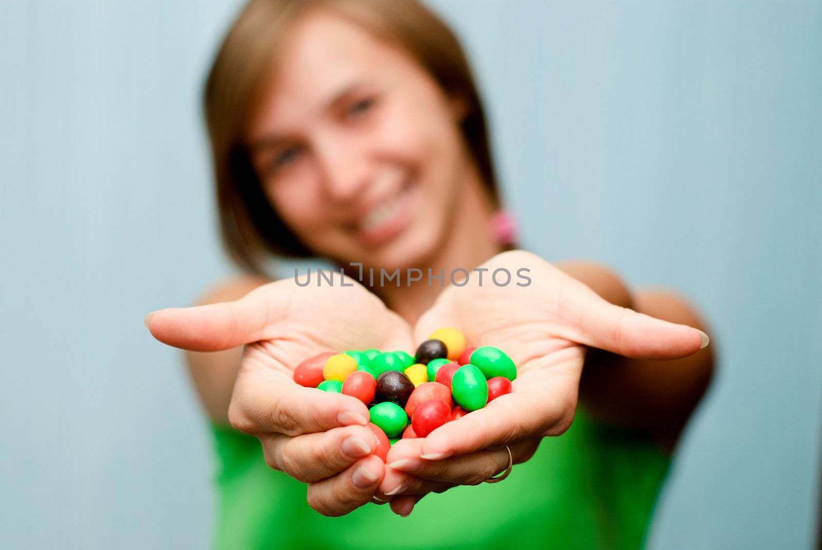 Portrait of a young woman offering colorful candies
