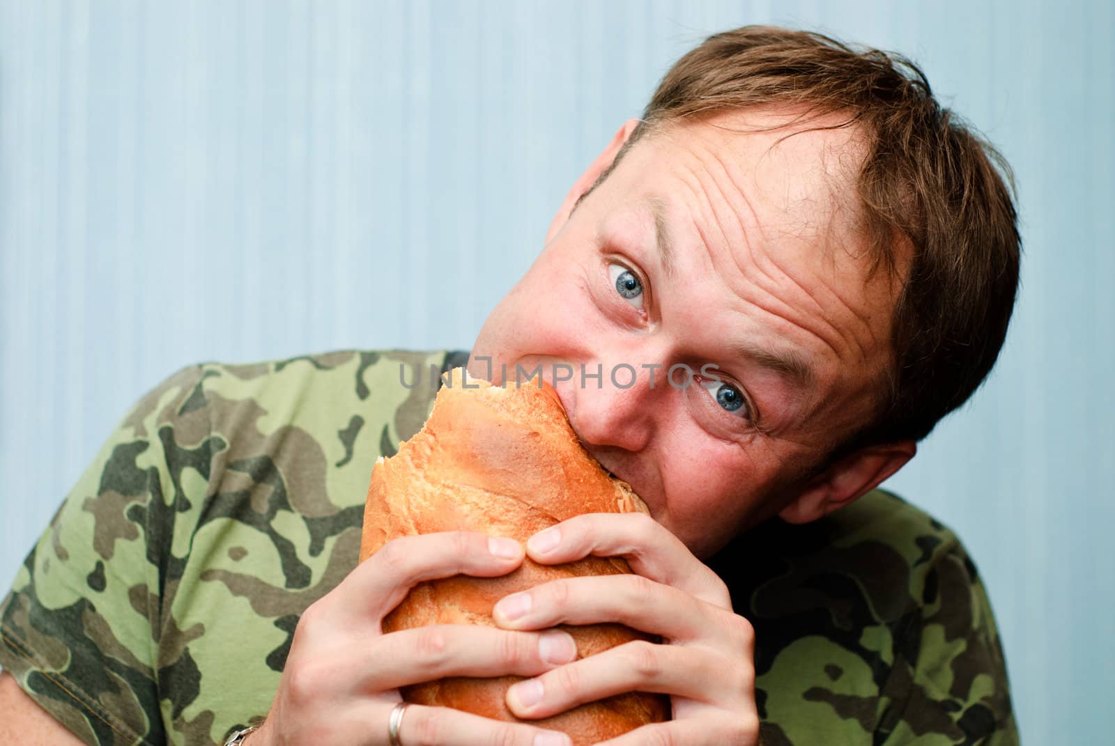 Portrait of a man in camouflage with a loaf of bread