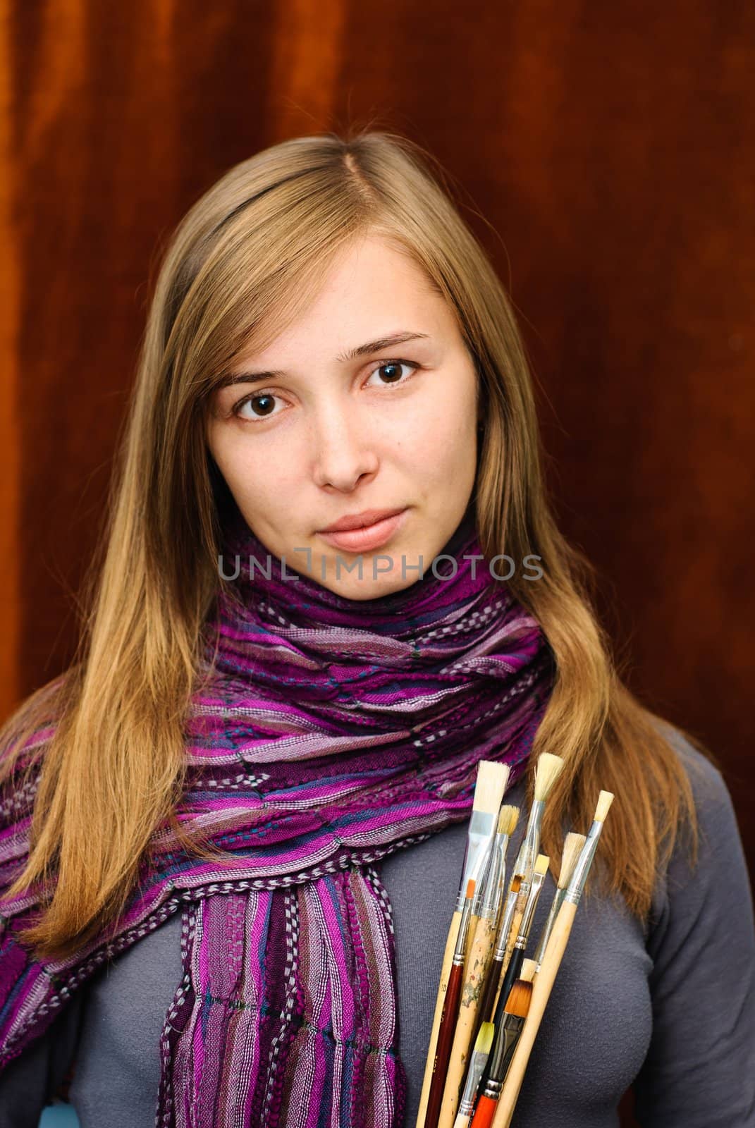 Portrait of young female artist with brushes