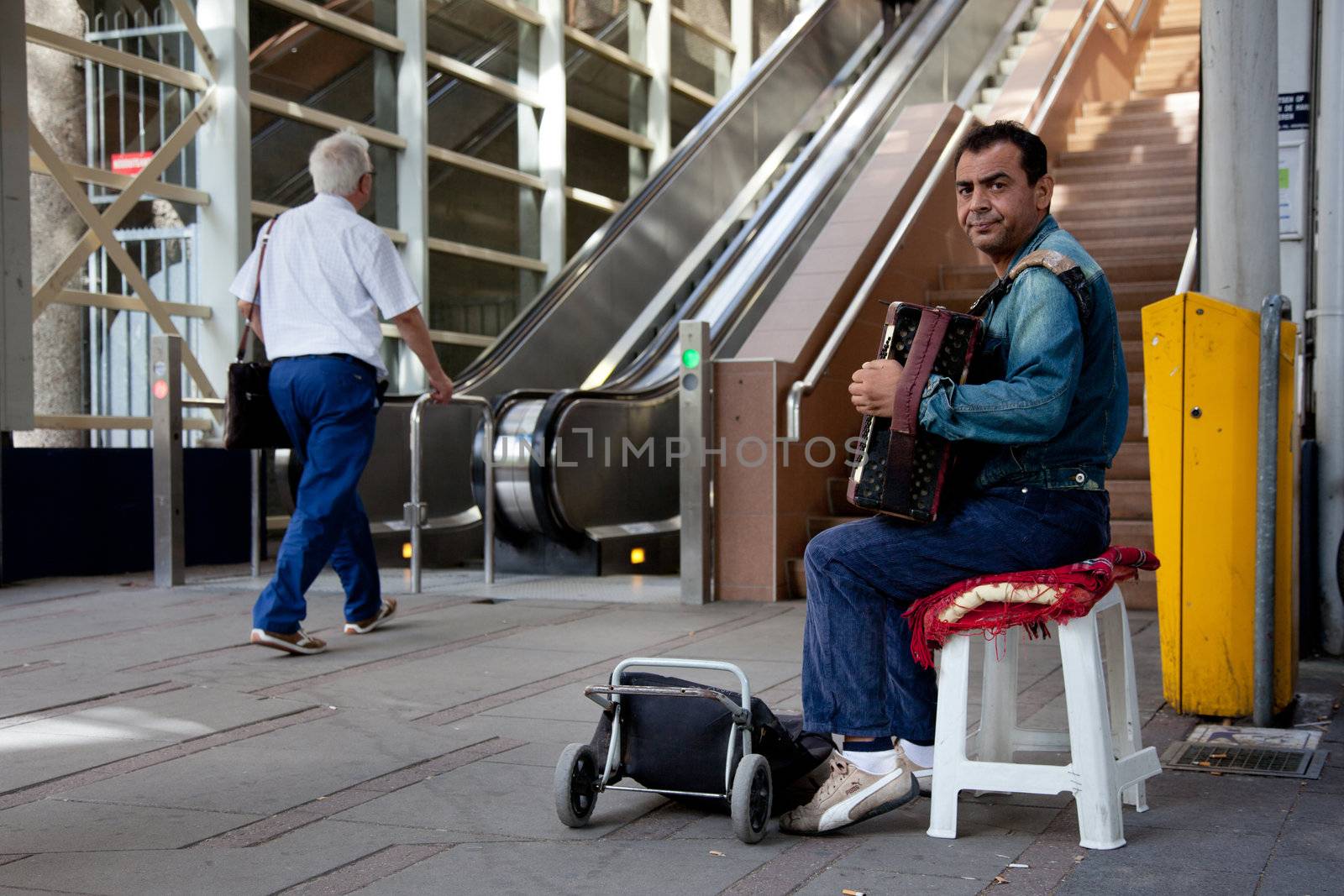 street musician playing accordion near stairs to shopping centre