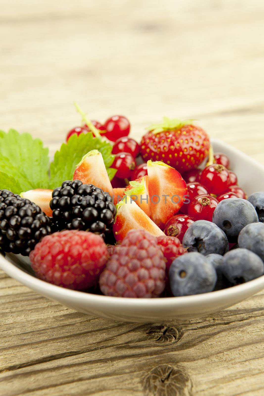 mixed fresh berries for dessert on wooden background in summer