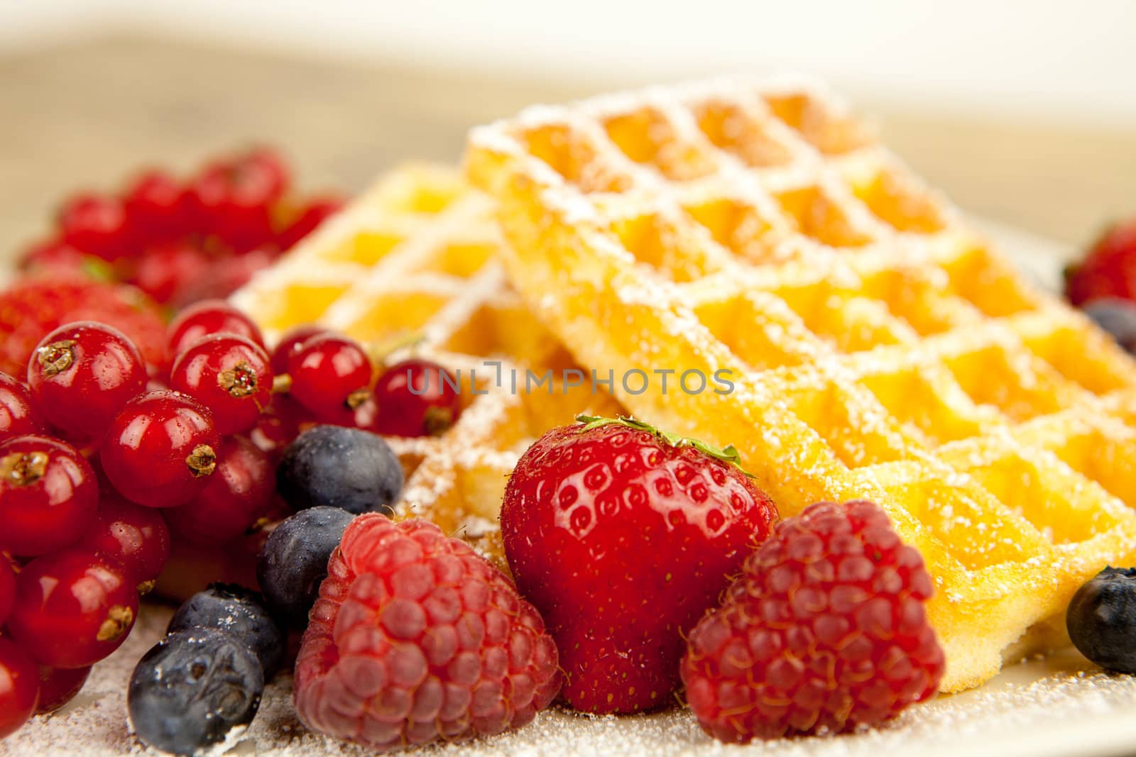 fresh tasty waffer with powder sugar and mixed fruits on wooden background