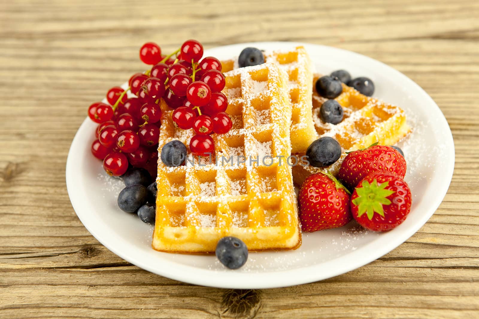 fresh tasty waffer with powder sugar and mixed fruits on wooden background