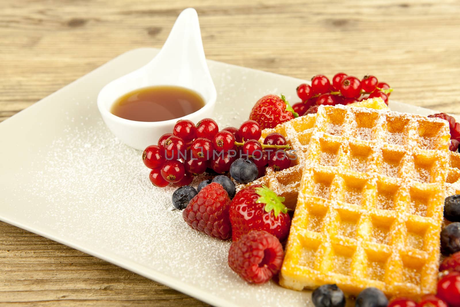 fresh tasty waffer with powder sugar and mixed fruits on wooden background