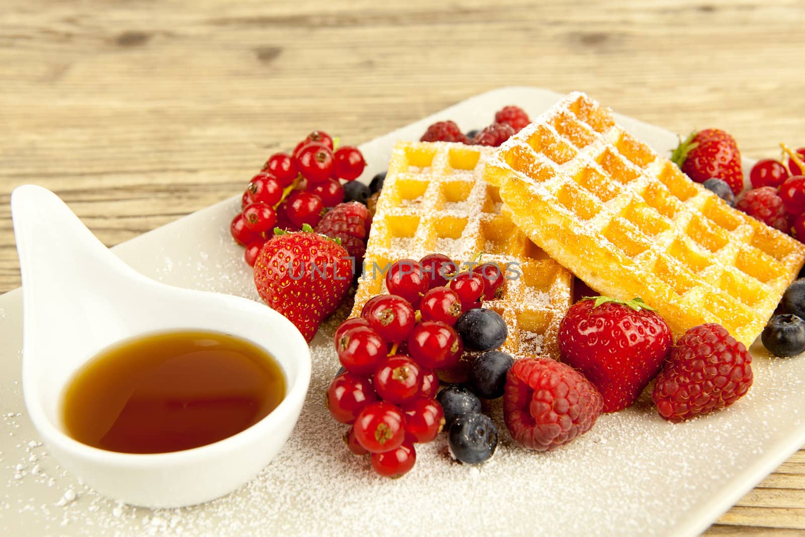 fresh tasty waffer with powder sugar and mixed fruits on wooden background