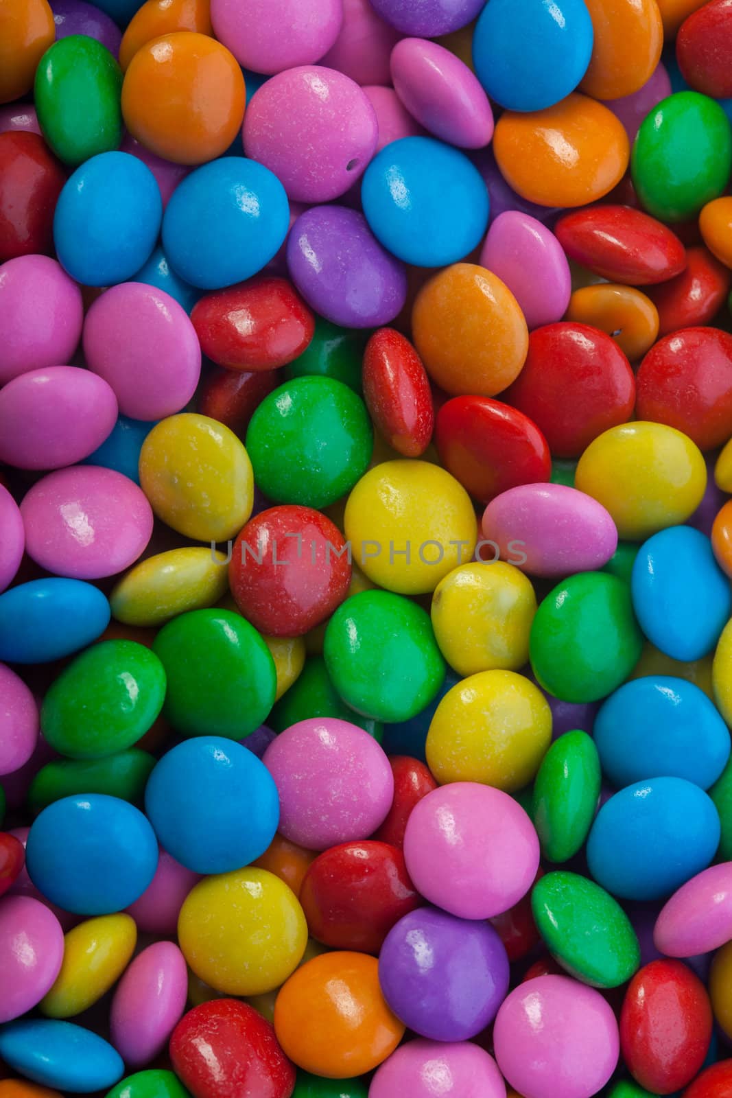 A bunch of chocolate buttons, in various colors such as pink, purple and yellow.