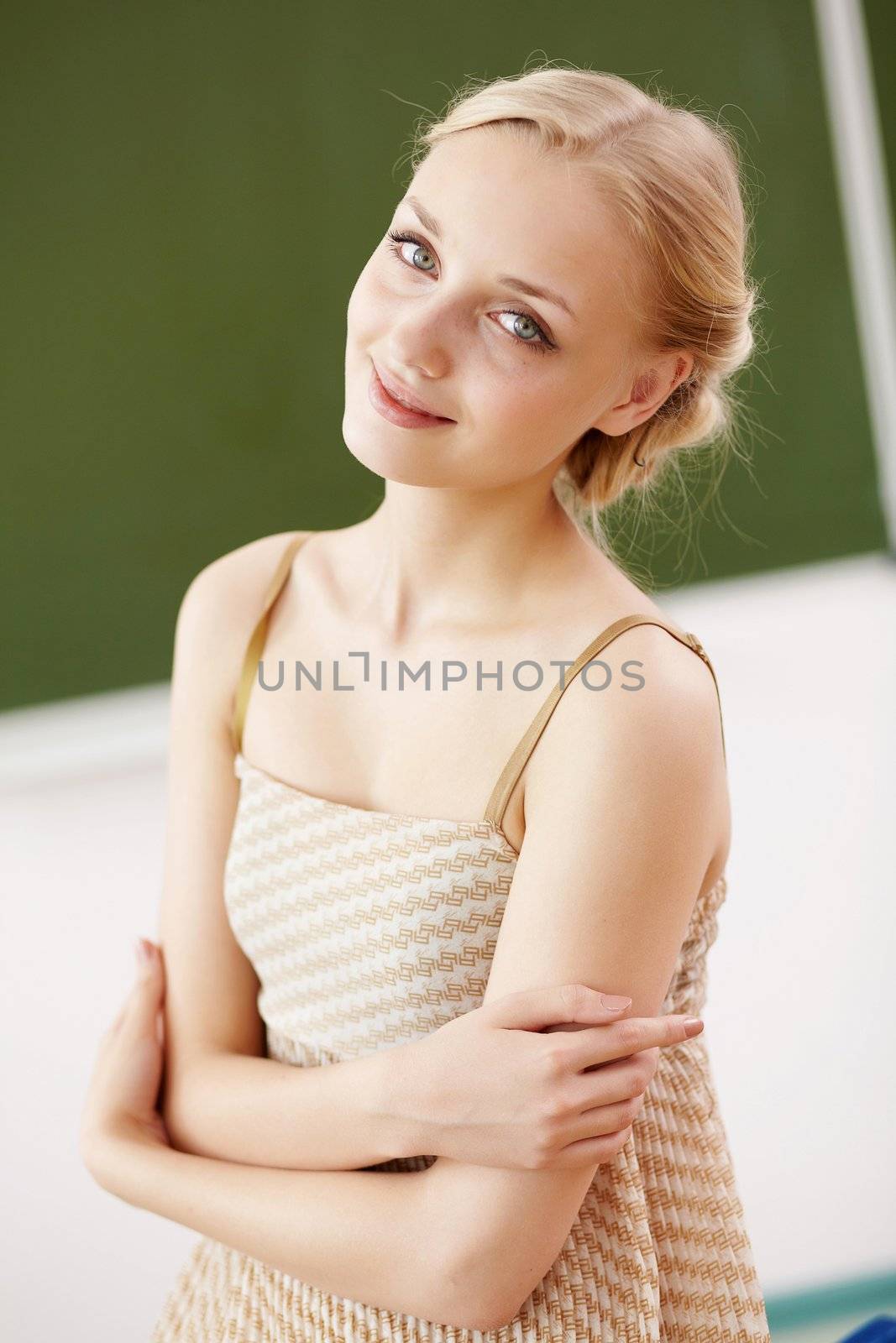 Young female teacher standing near blackboard at school