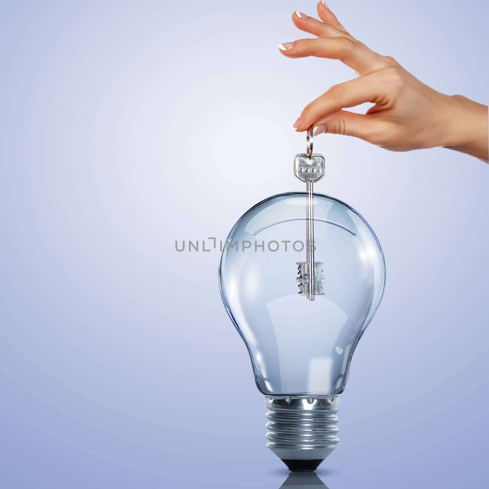 Hand holding a key and putting it inside a light bulb