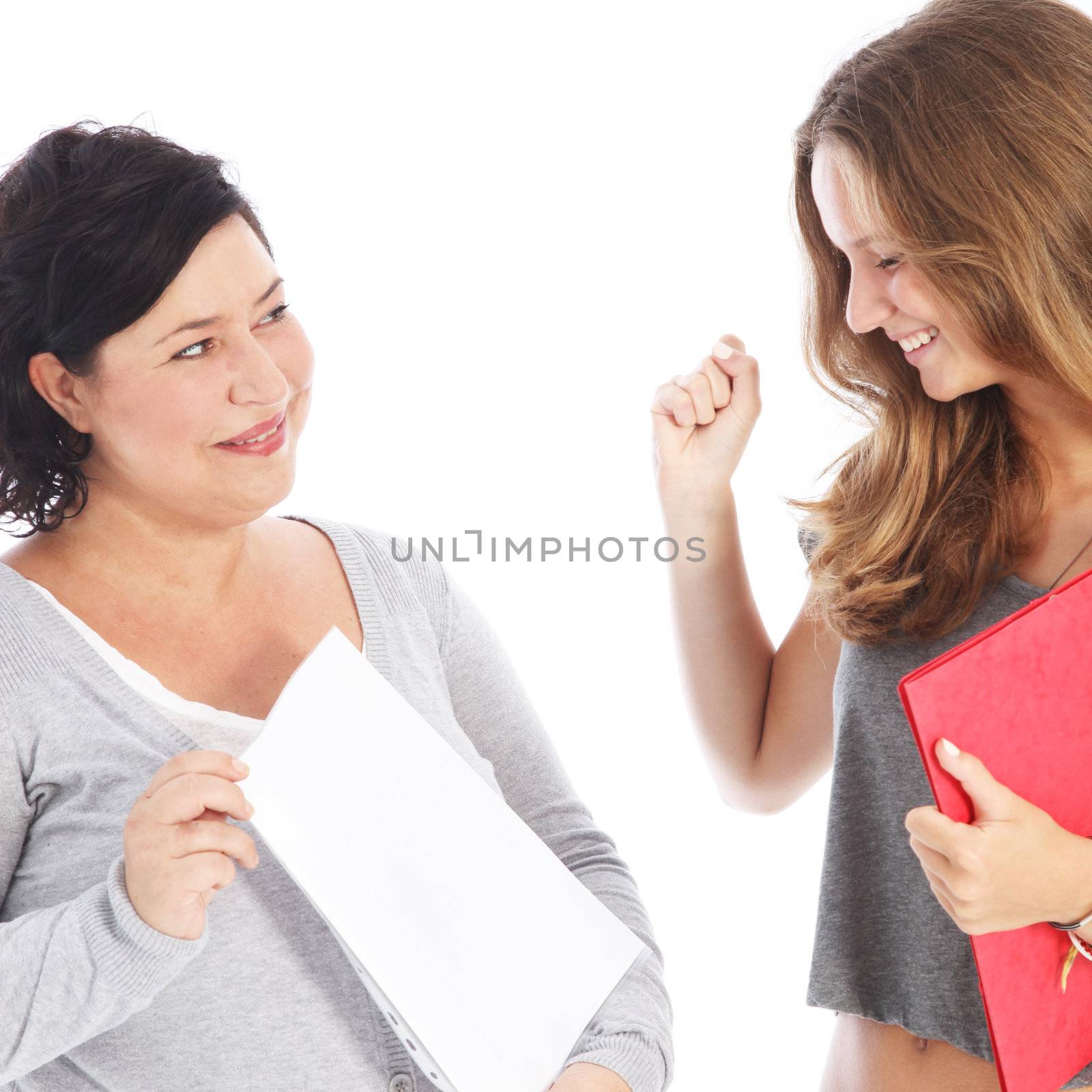 A middle-aged teacher holds up a blank sheet of paper showing a young female student her successful results A middle-aged teacher holds up a blank sheet of paper showing a young female student her results 