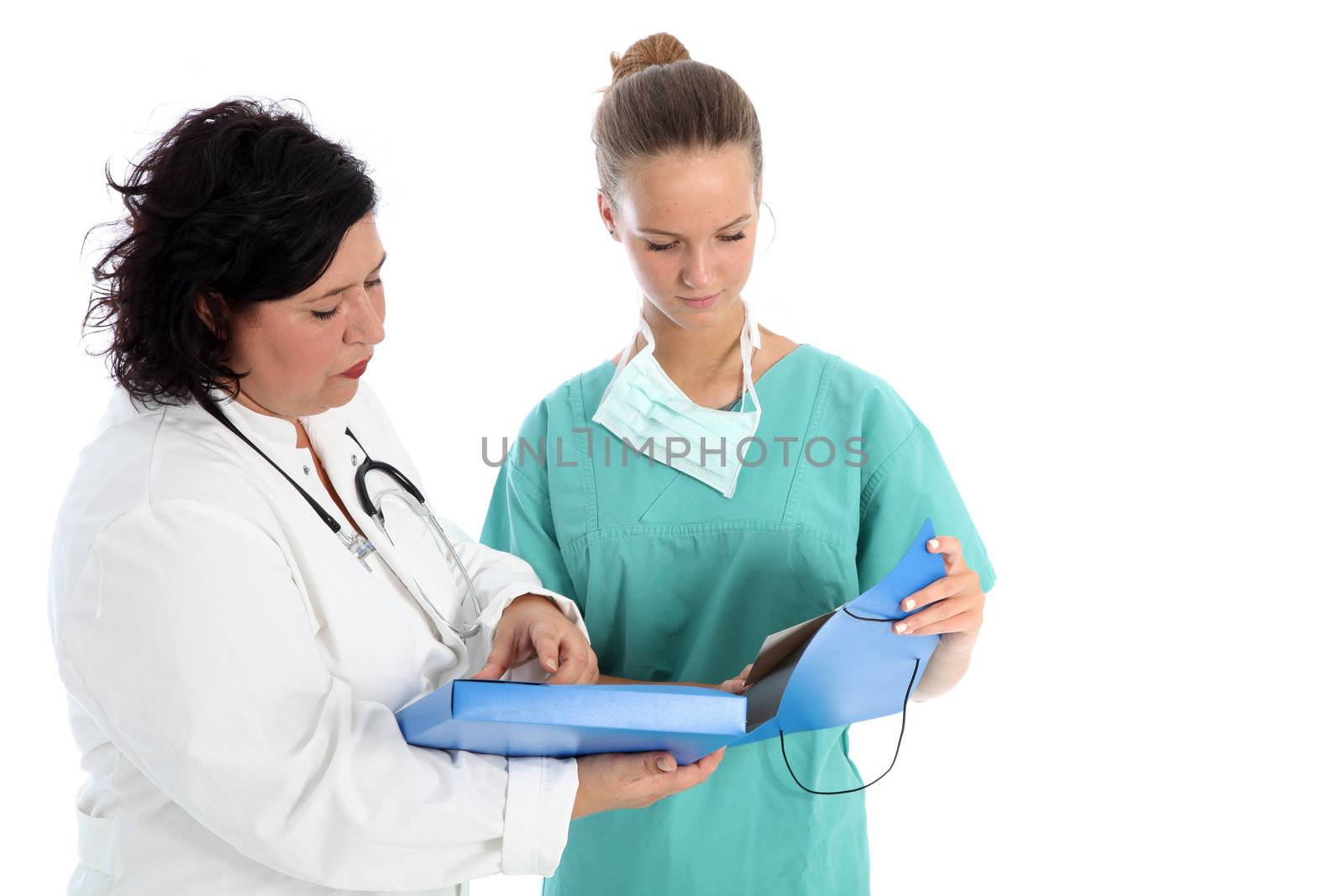 A female doctor and nurse stand close together with a large open folder discussing patient records isolated on white A female doctor and nurse stand close together with a large open folder discussing patient records 