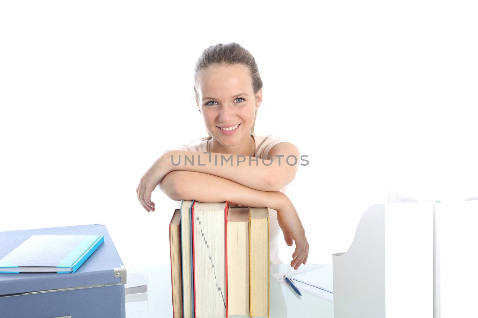 Confident young female student smiling as she leans on a row of large text books isolated on white 